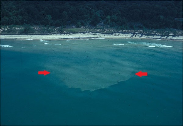 Sediment in water being transported offshore from a beach by a rip current.